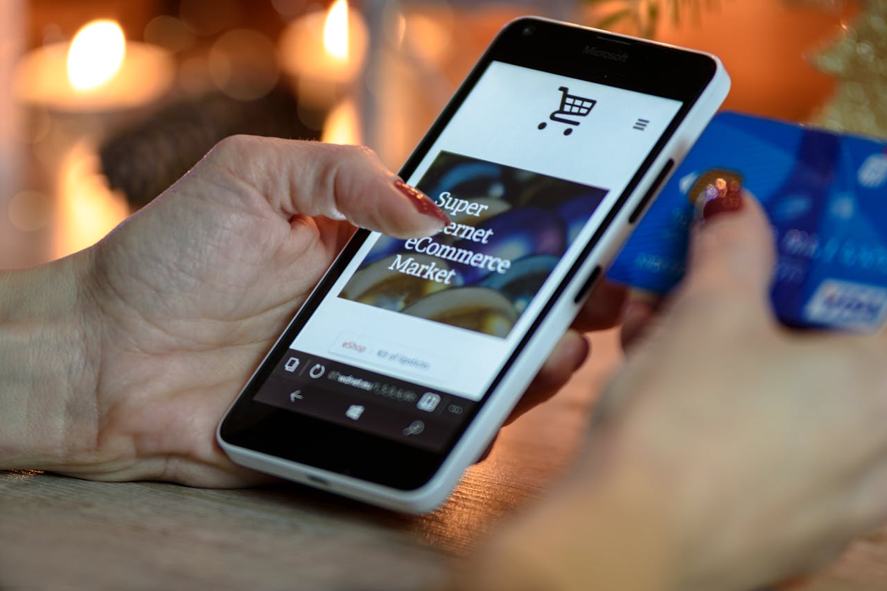 about-us Woman using smartphone for online shopping with credit card in hand, festive background lighting.