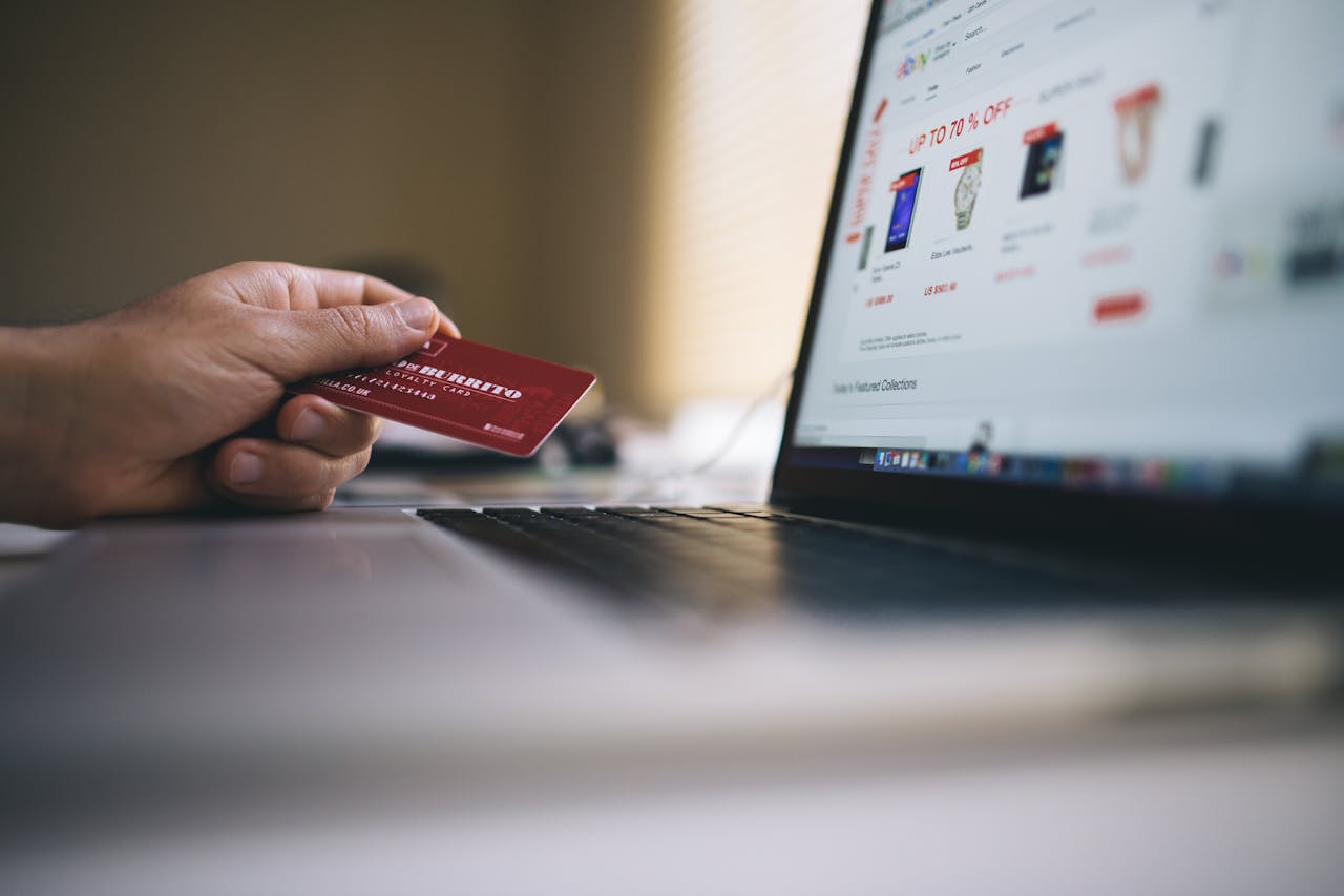 heros-img Person holding a credit card while shopping online on a laptop, indicating ecommerce transactions.